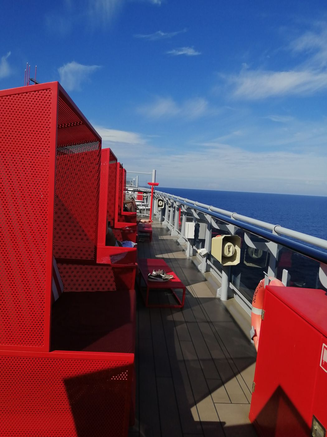 Red shaded loungers lined up along the ship's deck above the ocean