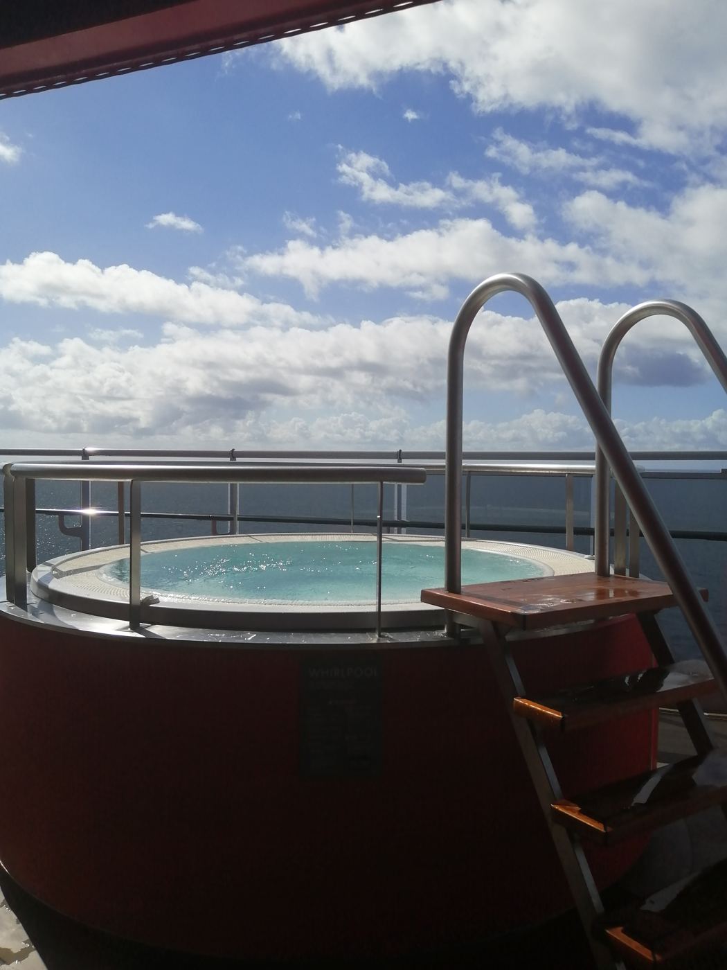 A hot tub on the open deck with blue sky and sea beyond